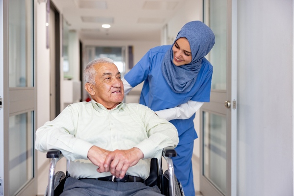 A Muslim nurse takes care of a senior patient in a wheelchair.